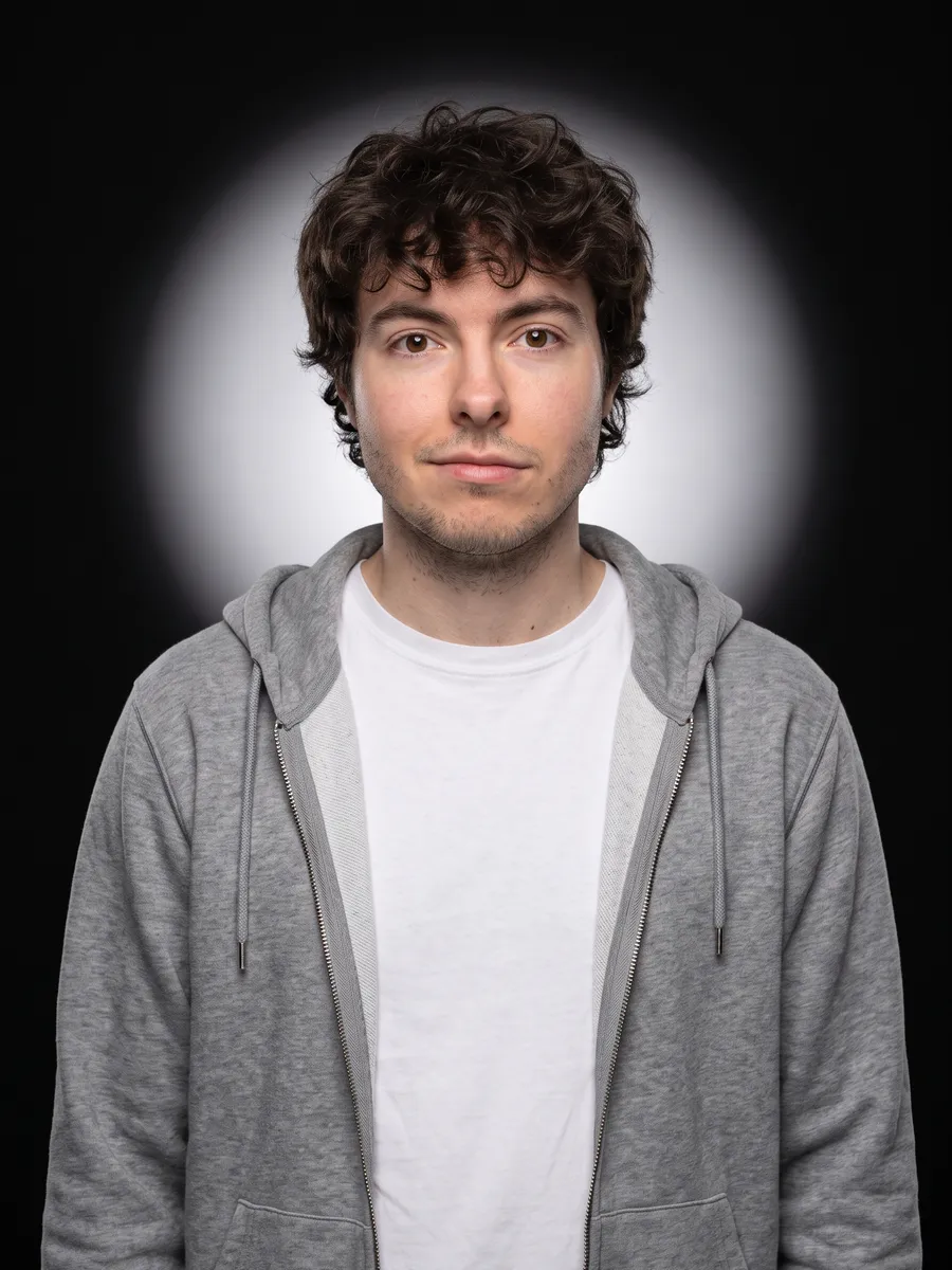 Portrait d’Odilon Buisson généré par IA : buste de face, sweat à capuche gris ouvert sur un tee-shirt blanc, halo de lumière derrière la tête.